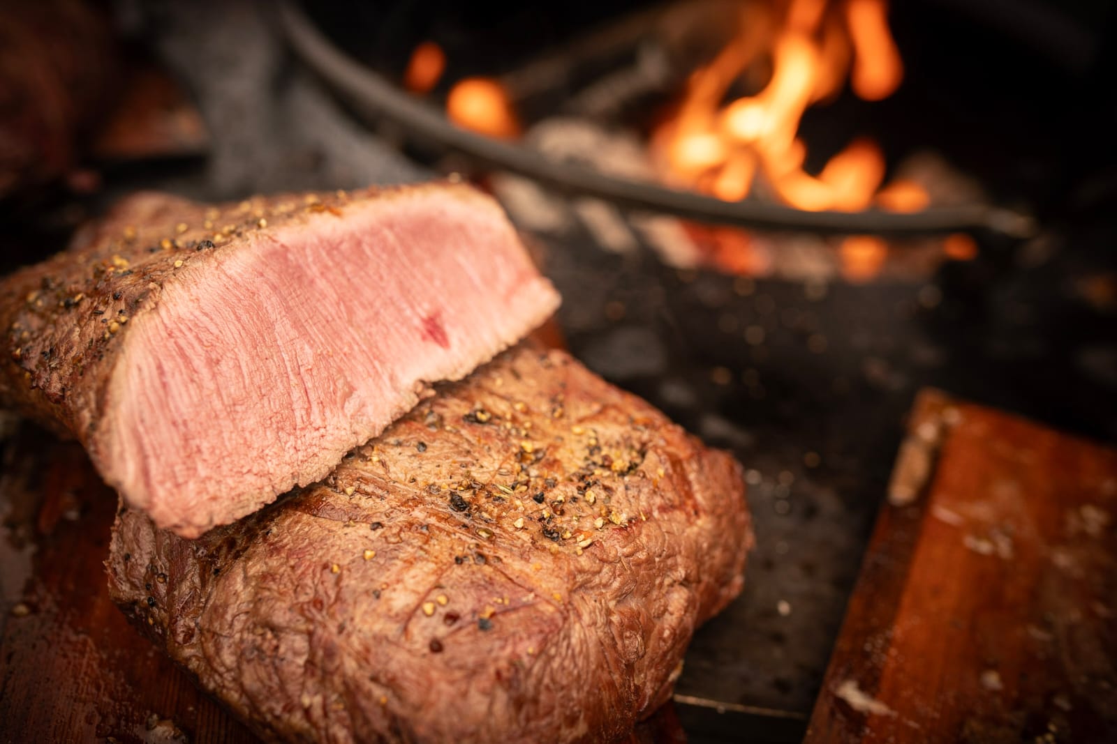 Aufgeschnittenes Roastbeef in Großaufnahme, im Hintergrund die Flammen des Ofyr