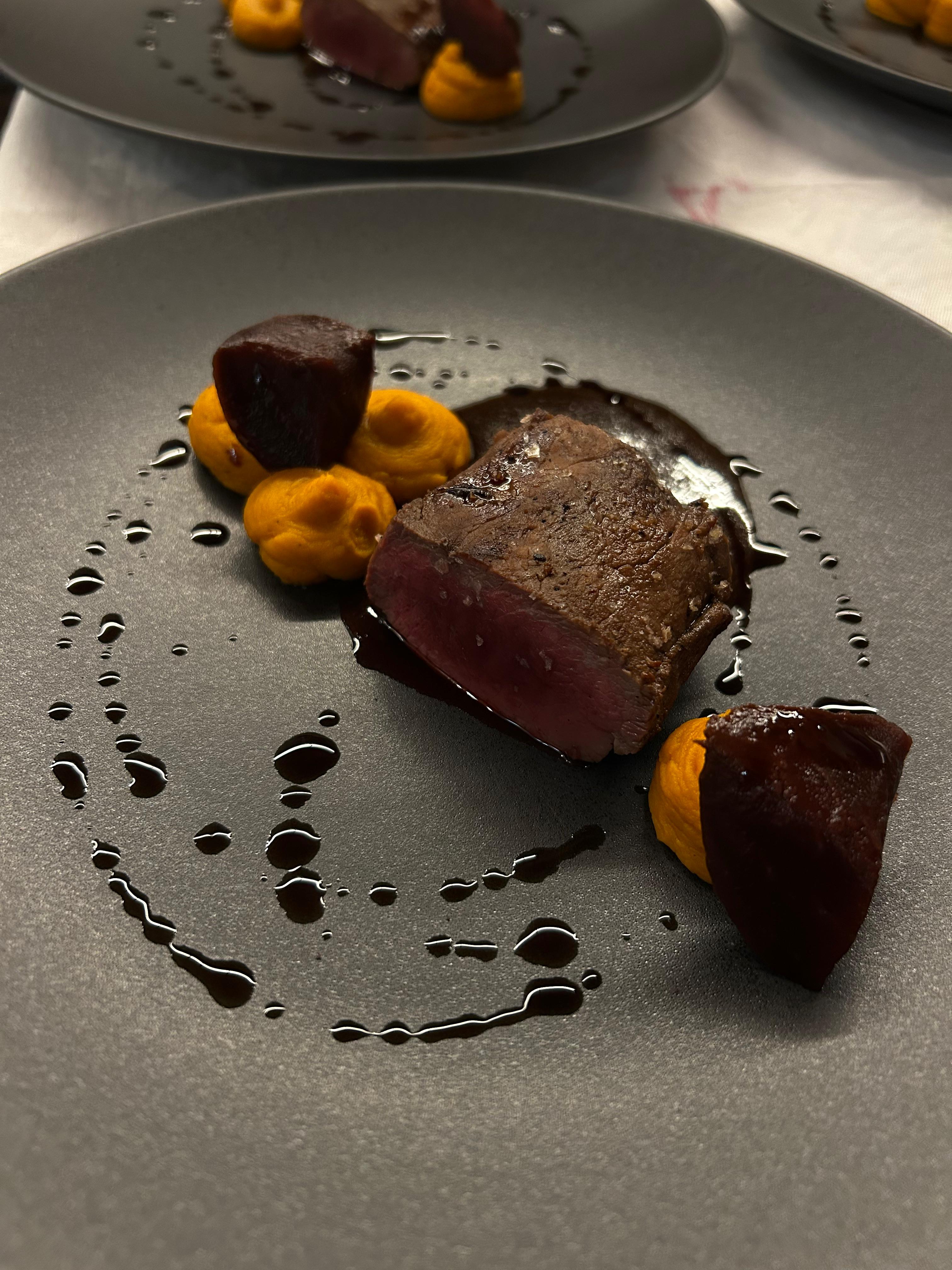 Wildfilet medium auf Karotten-Püree mit Rote-Bete-Würfeln und Jus, eleganter dunkler Teller