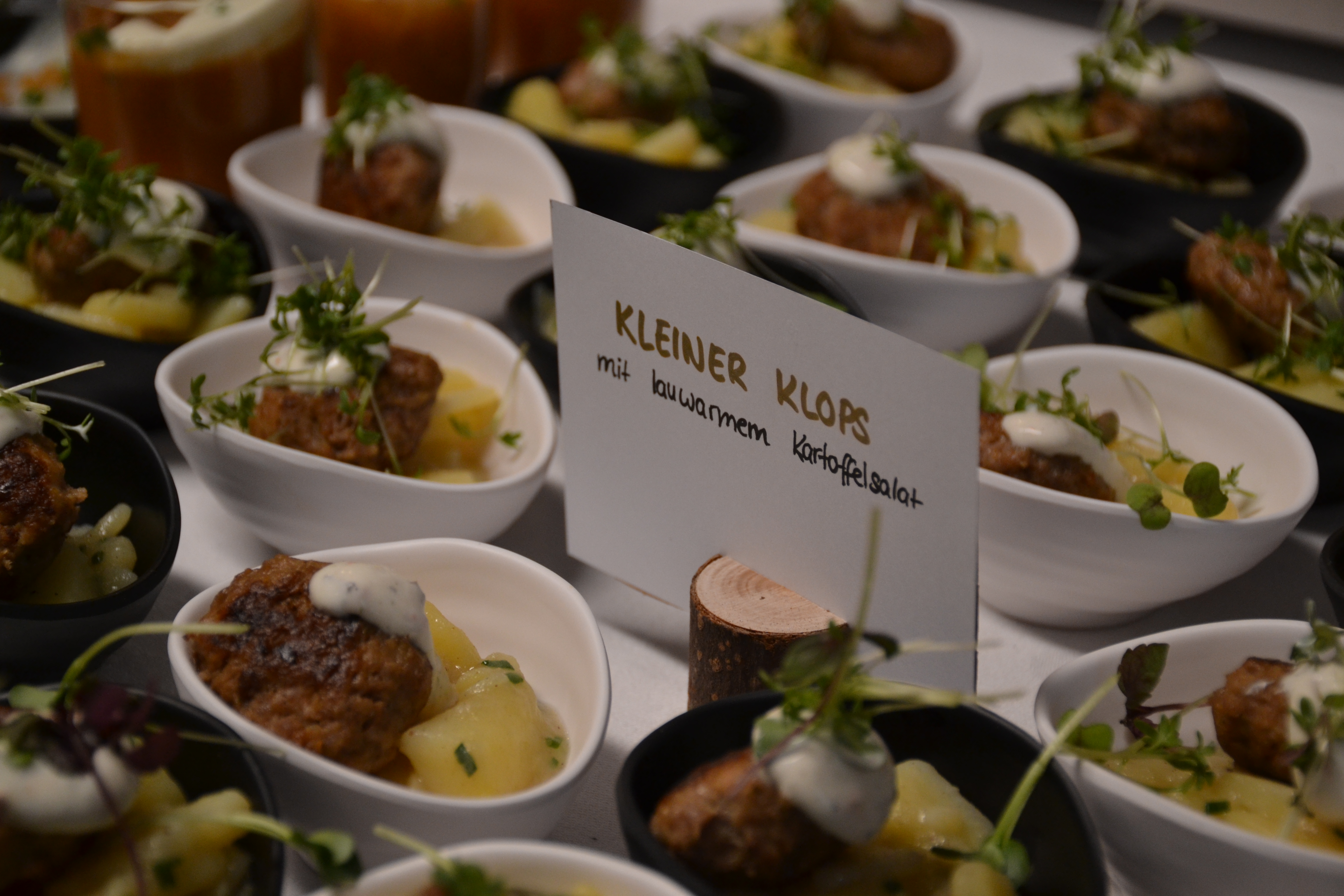Apéritif-Schälchen mit Mini-Frikadelle und lauwarmem Kartoffelsalat, dazu handgeschriebene Beschriftung