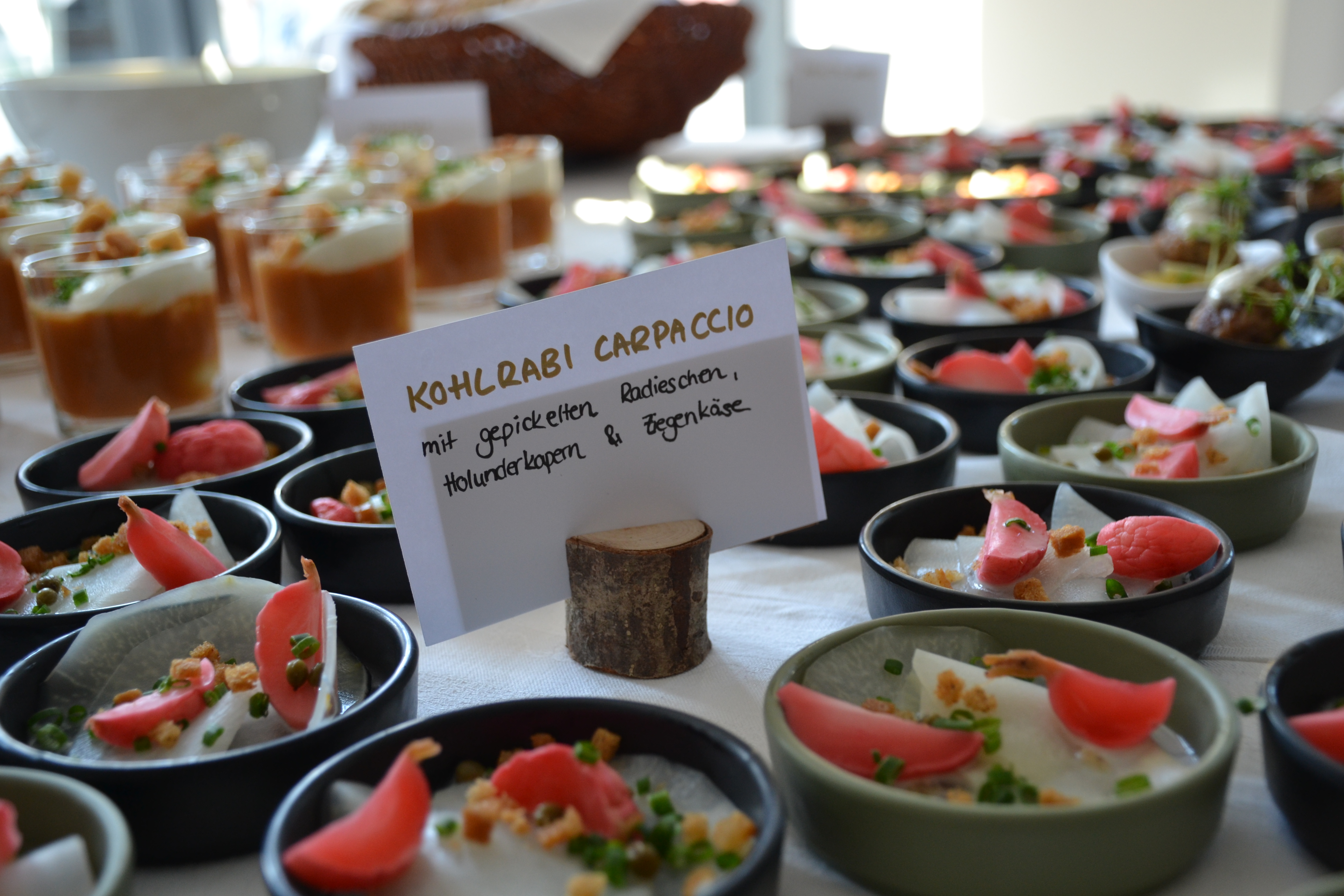 Kohlrabi-Carpaccio mit gepickelten Radieschen, Holunderkapern und Ziegenkäse, mit Beschriftungs-Schild