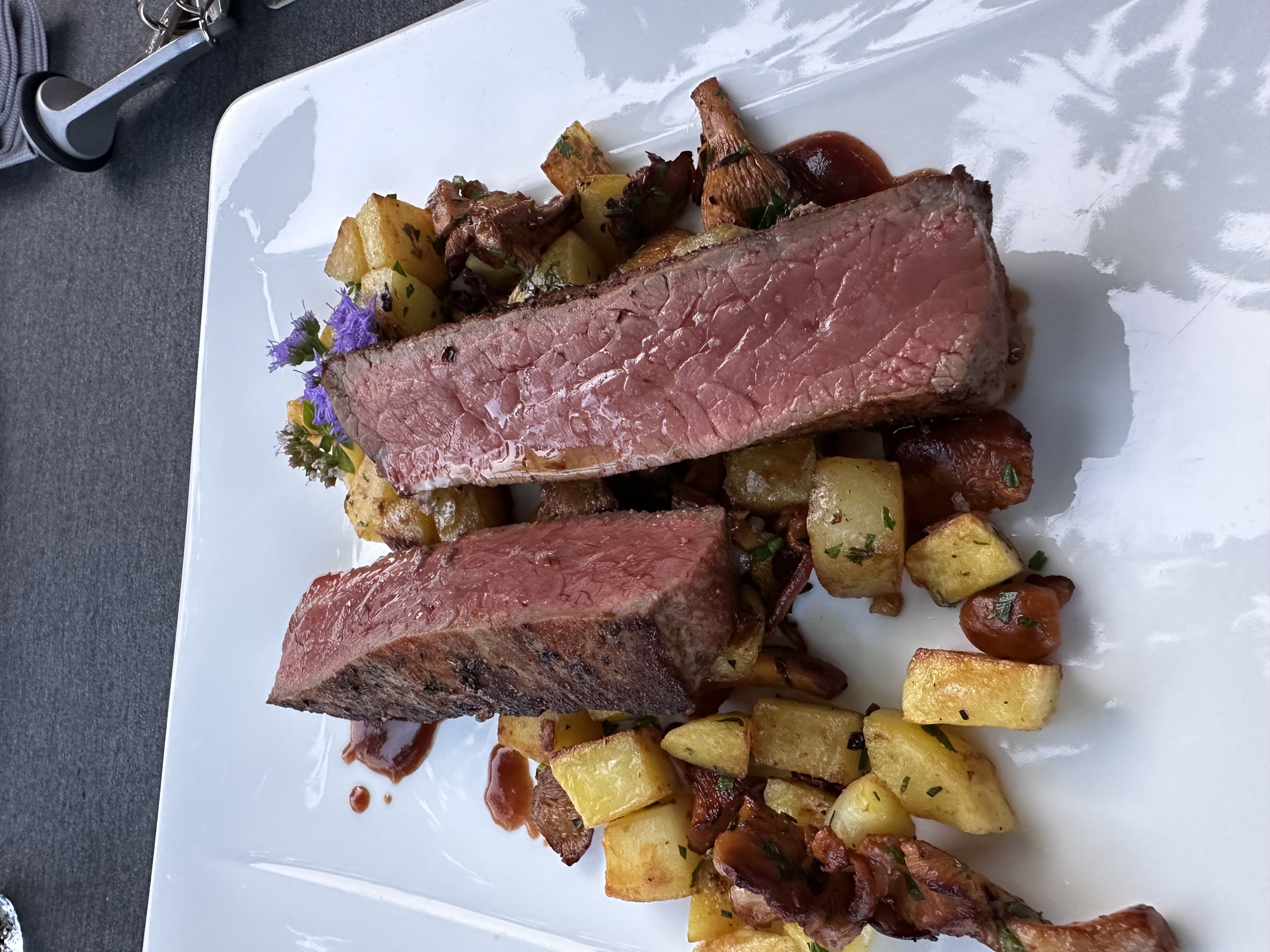 Aufgeschnittenes Roastbeef mit gerösteten Pfifferlingen und Bratkartoffeln auf weißem Teller