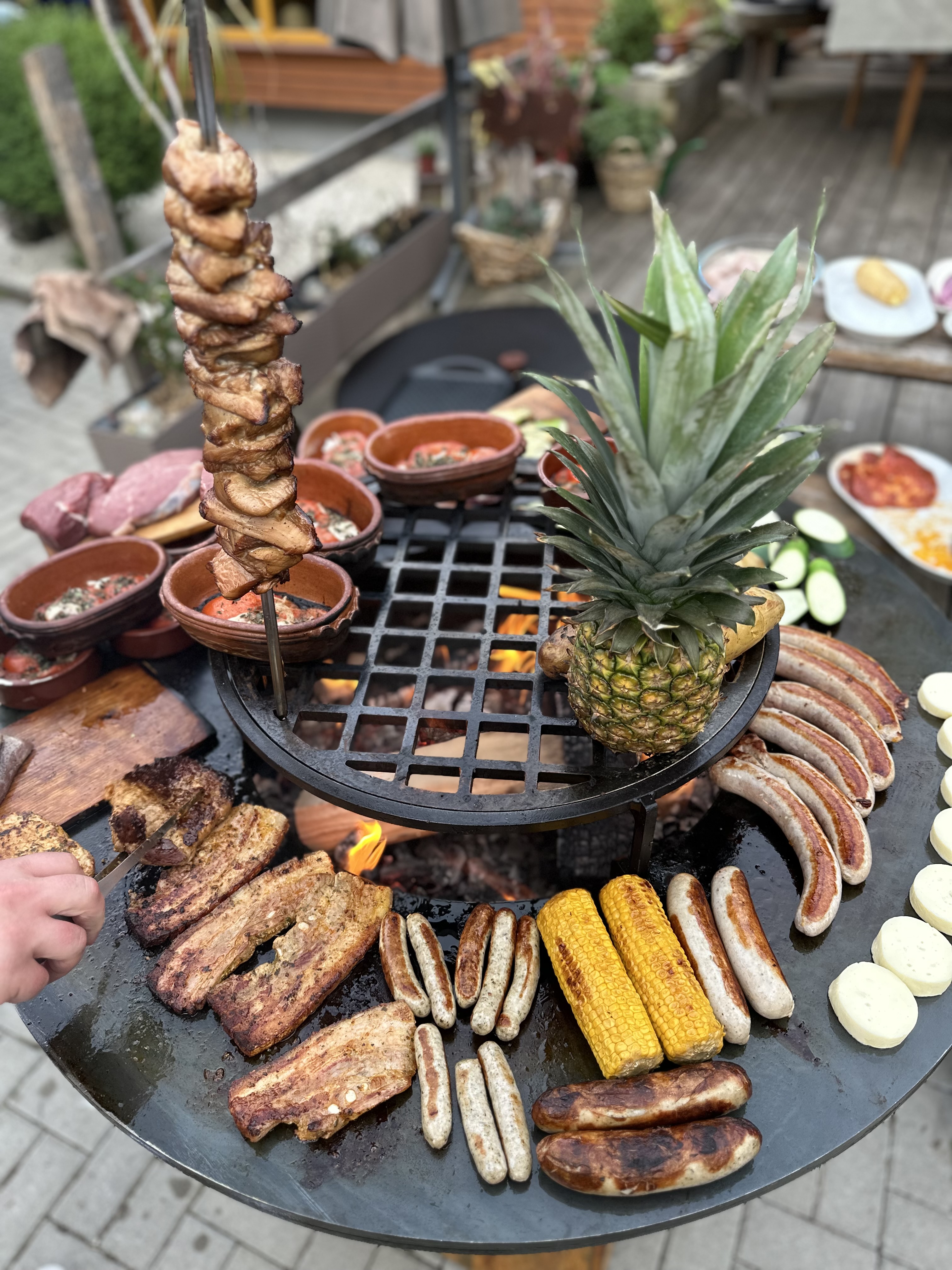 Reichhaltiges Outdoor-Buffet am Ofyr — Spieße, Würste, Maiskolben, Steaks und tropische Akzente